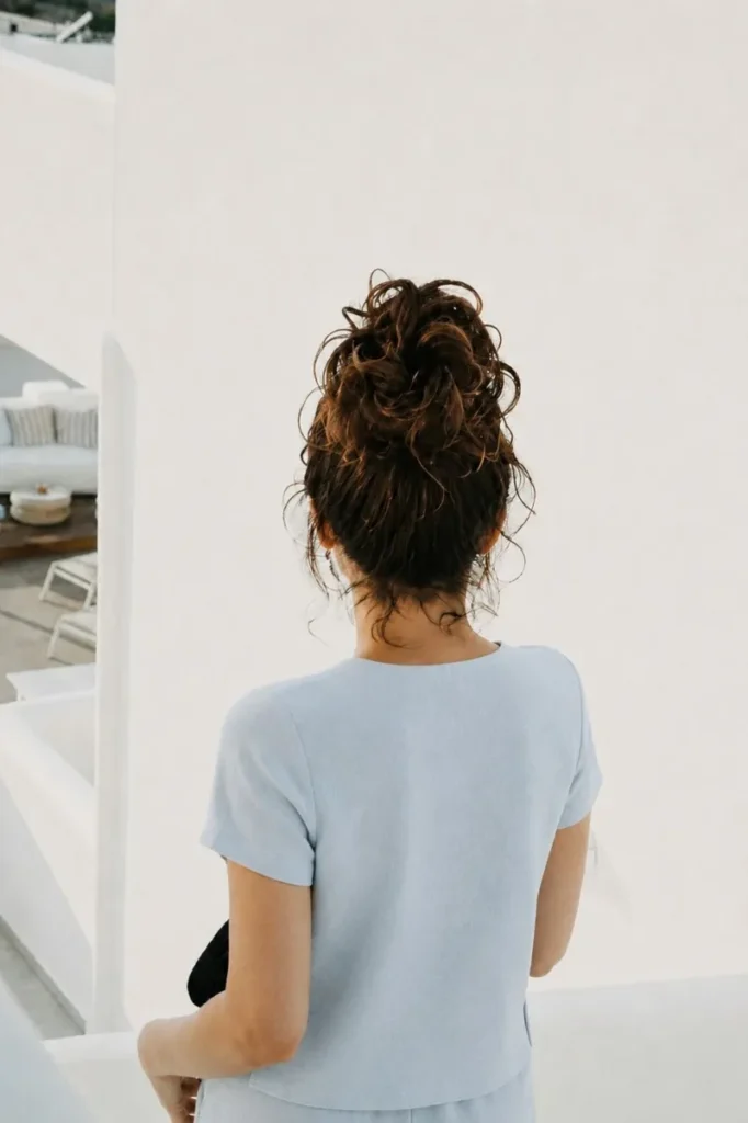 Jakolien Sok seen from behind, curly bun and a light blue top