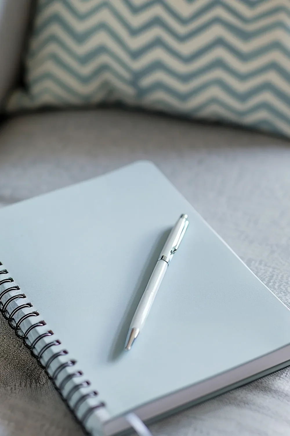 Pale blue spiral notebook with a pen resting on top